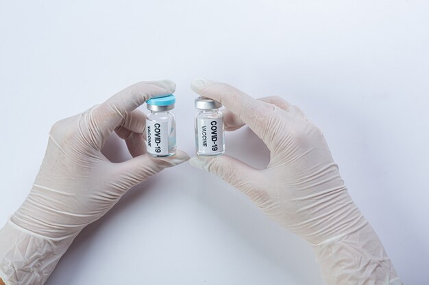 Close up a vial of covid-19 vaccine in hand of a scientist or doctor