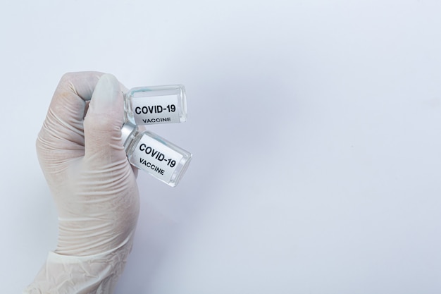 Close up a vial of covid-19 vaccine in hand of a scientist or doctor