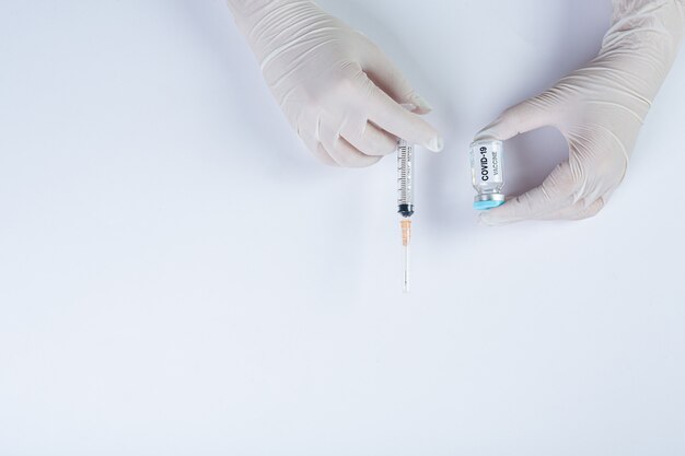 科学者または医師の手でcovid-19ワクチンのバイアルを閉じます