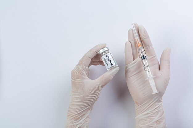 Закройте флакон с вакциной covid-19 в руке ученого или врача