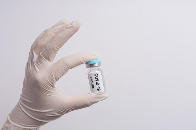 Close up a vial of covid-19 vaccine in hand of a scientist or doctor