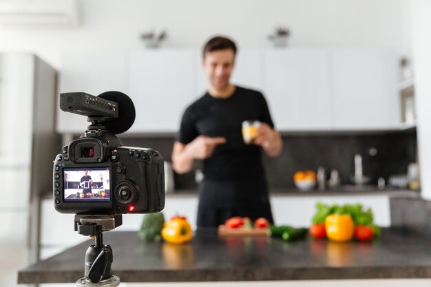 Close up of a video camera filming smiling male blogger