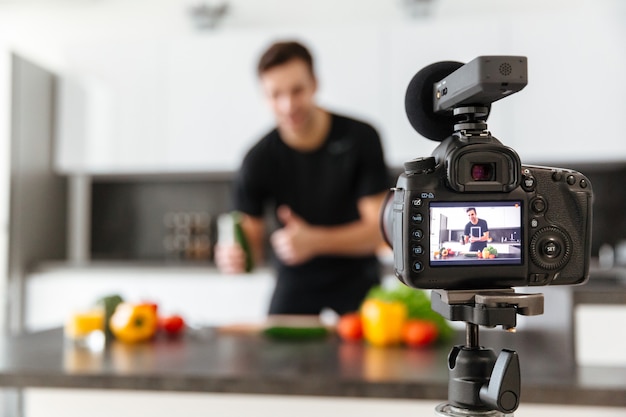 Close up of a video camera filming young smiling male blogger