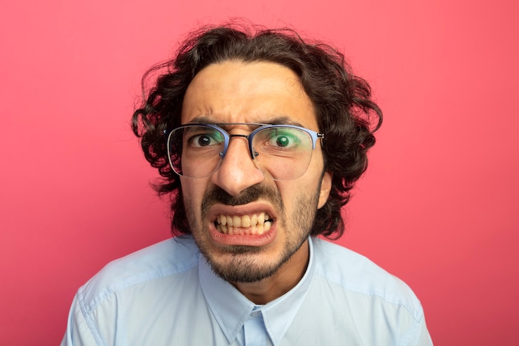 मुफ़्त फोटो close-up view of annoyed young handsome man wearing glasses looking at front isolated on pink wall