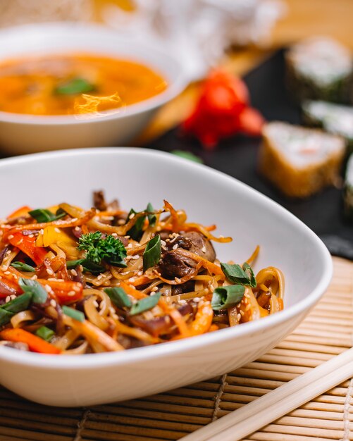 Close up view of asian stir fried noodles with beef peppers and onions in a bowl