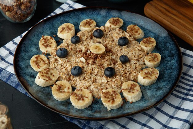 Close up view of banana blackthorn walnut oatmeal in plate on plaid cloth with walnuts on black background