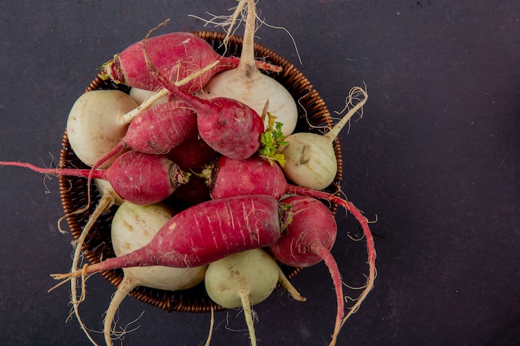 Free Photo close-up view of basket full of radishes on maroon background with copy space