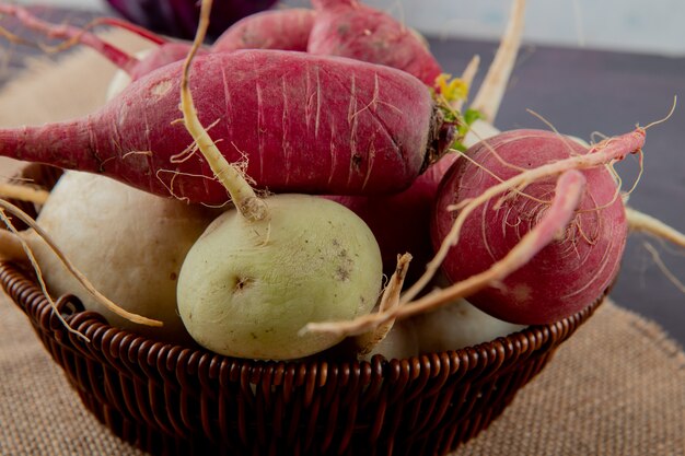 Close-up view of basket of red and white radishes on sackcloth surface