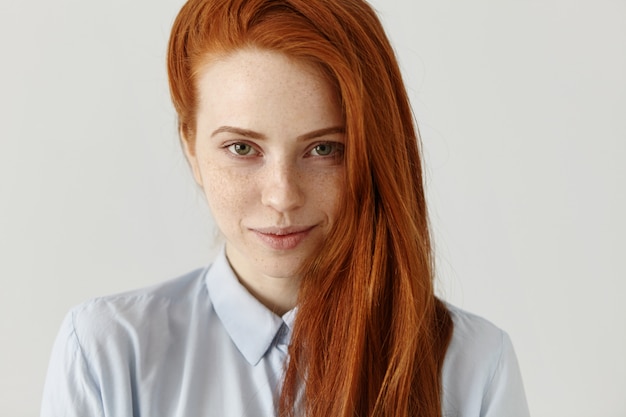 Foto gratuita chiuda sulla vista di bella donna caucasica felice con i capelli e le lentiggini dello zenzero che guardano e che sorridono