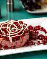 Free photo close up view of beetroot salad with vegetables topped with mayonnaise and pomegranate beans on platter