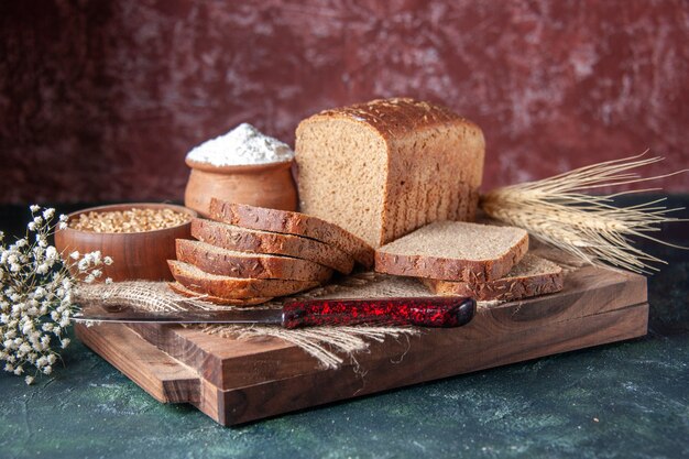 Close up view of black bread slices on nude color towel spikes flower on cutting boards on mixed colors background