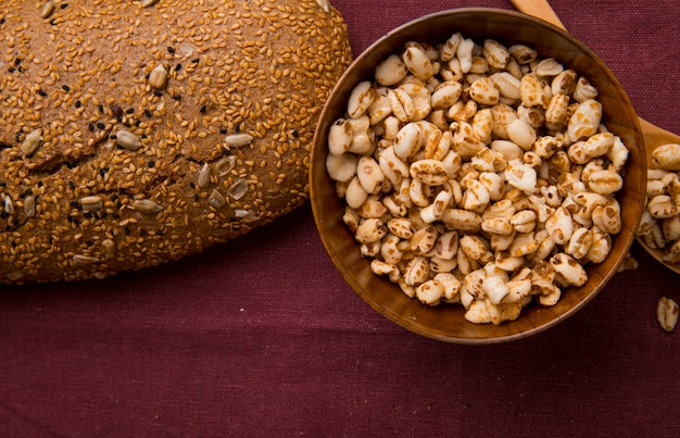 Close-up view of bowl full of corns and seeded cob on burgundy background with copy space