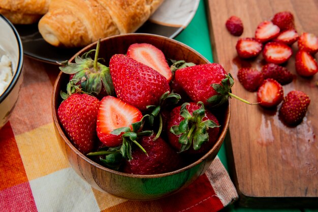 천으로 접시에 초승달 롤과 커팅 보드에 딸기를 잘라 딸기 그릇의 근접 촬영보기