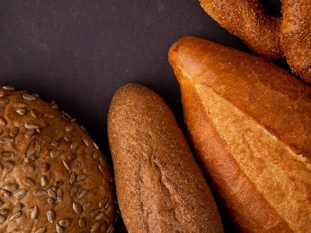 Close-up view of breads as cob baguette bagel on maroon background with copy space