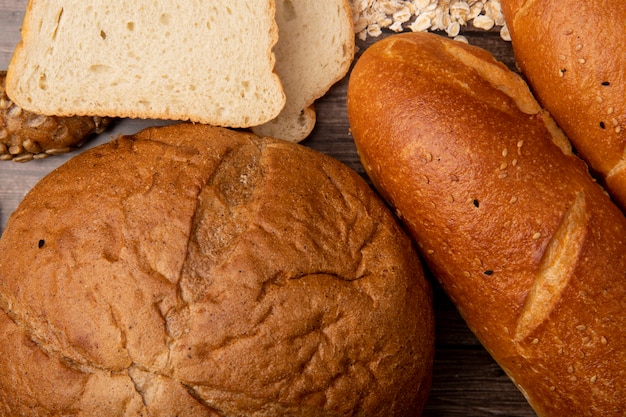 Foto gratuita vista del primo piano dei pani come pannocchia e baguette con le fette del pane bianco su fondo di legno