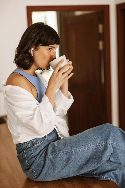 Close up view of brunette hair woman drinking coffee in hand listening music