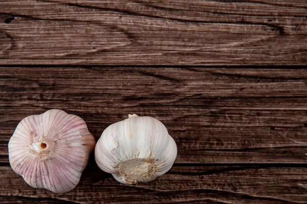 Free photo close-up view of bulbs of garlic on left side and wooden background with copy space