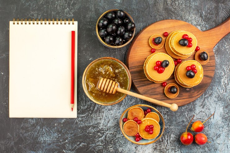 Free Photo close up view of buttermilk pancakes with fruits honey fruits and notebook
