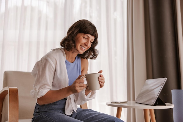 Close up view of caucasian woman looking and smiling at cup of coffee