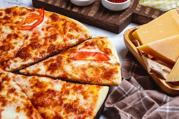 Close up view of cheese pizza with tomatoes on a wooden plate