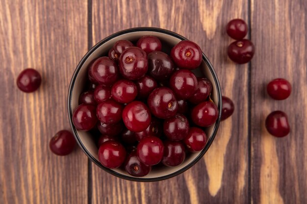 Close-up view of cherries in bowl and on wooden background