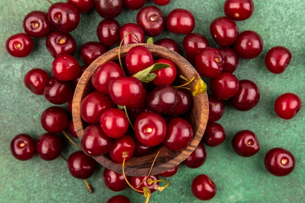 Free photo close-up view of cherries in wooden bowl and on green background