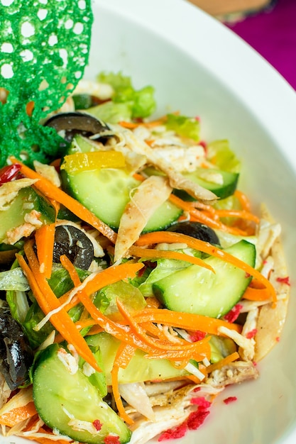 Free photo close up view of chicken salad with chopped fresh vegetables and black olives in a bowl