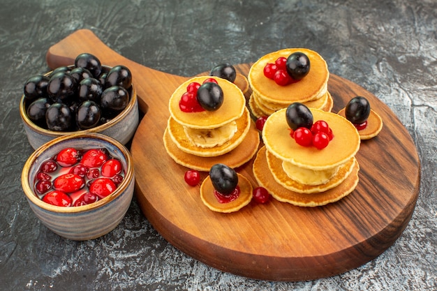 Close up view of classic buttermilk pancakes served with fruits on gray