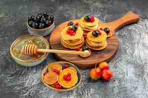 Free photo close up view of classic pancakes on cutting board honey and fruits