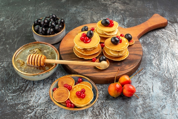 Close up view of classic pancakes on cutting board honey and fruits