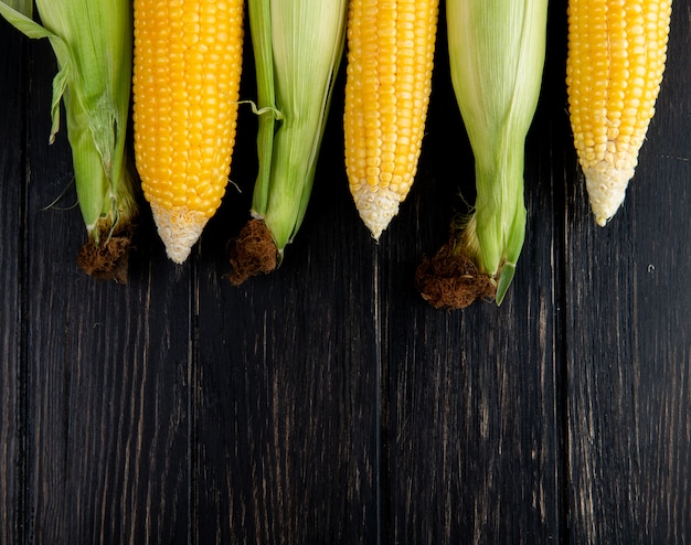 Close-up view of cooked and uncooked corns on black background with copy space