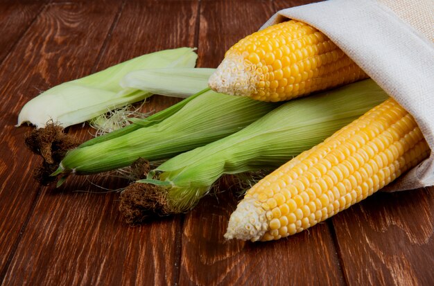 Close-up view of cooked and uncooked corns in sack on wooden surface