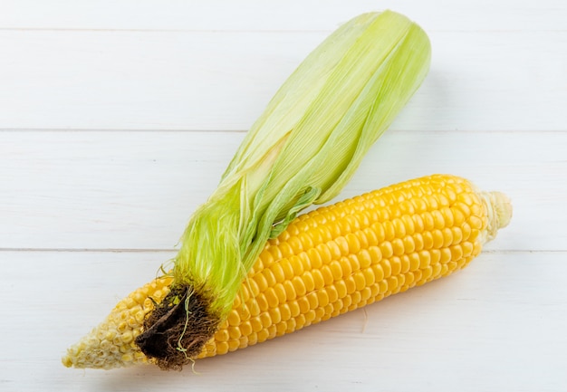 Close-up view of cooked and uncooked corns on wooden surface