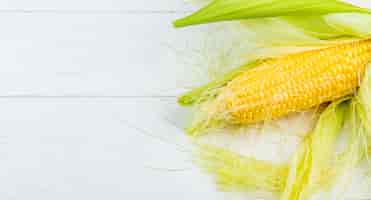 Free photo close-up view of corn cob on right side and wooden background with copy space