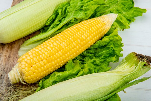 Close-up view of corn cobs and lettuce on wooden table