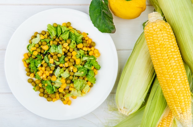 Close-up view of corn salad and corn cobs with lemon on wooden table