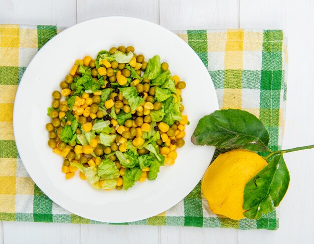 Close-up view of corn salad and lemon on cloth and wooden table