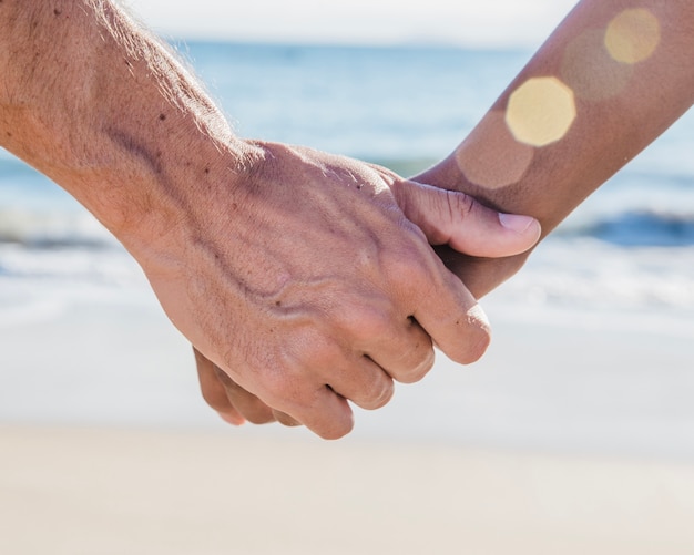 Close up view of couple holding hands at the beach