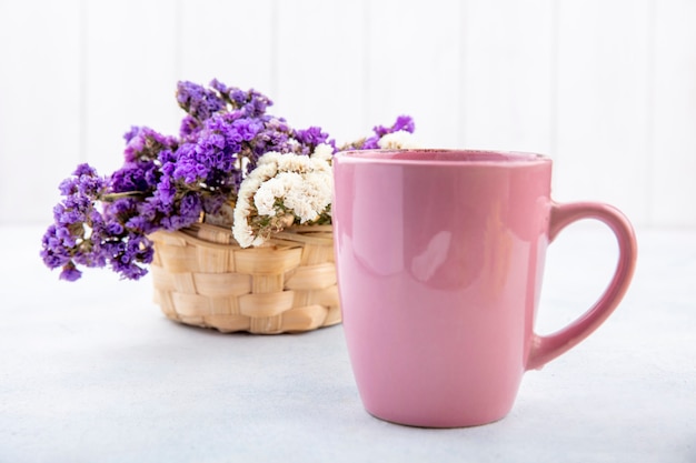 Close up view of cup of tea with flowers on white surface