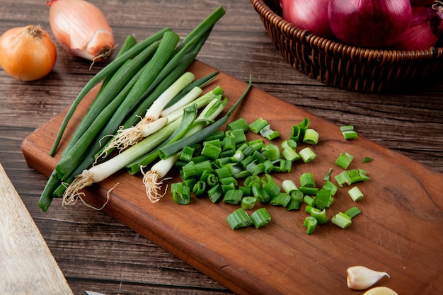 Close-up view of cut green onion on wooden surface and wooden background