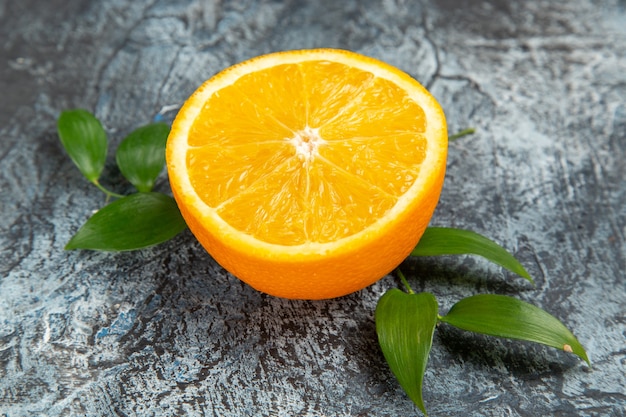 Close up view of cut in half fresh orange with leaves on gray background stock photo