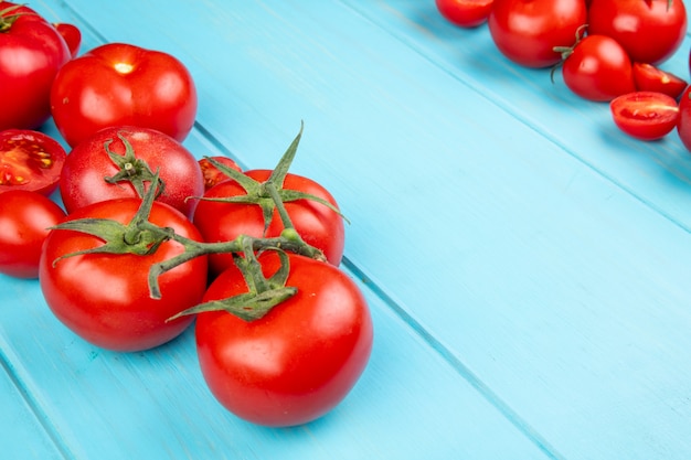 Close-up view of cut and whole tomatoes on blue background