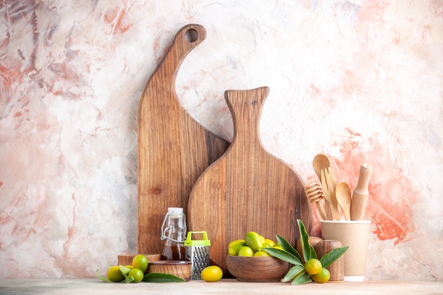 Close up view of cutting boards wooden spoons grater oil bottle and fresh kumquats on colorful surface