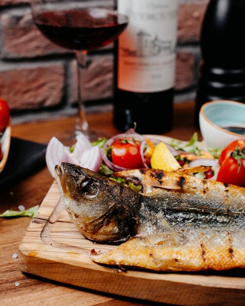 Close up view of deep fried sea bass served with fresh vegetables lemonnd narsharab sauce on wooden table