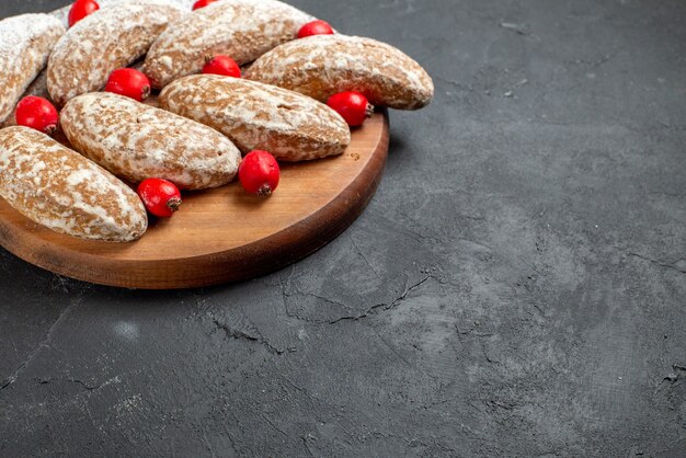 Close up view of delicious banana cookies with fruits on brown cutting board on dark