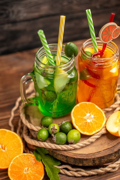 Close up view of delicious fresh juices and fruits on a wooden tray on a brown background