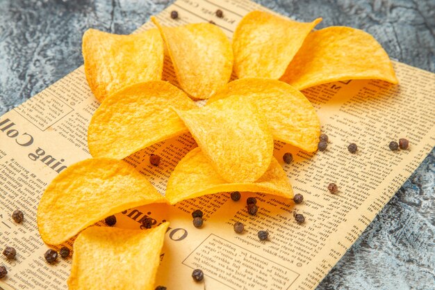 Close up view of delicious homemade chips on newspaper on gray table