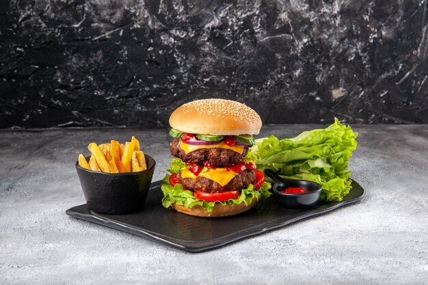 Close up view of delicious homemade sandwich and fork ketchup fries green on black tray on gray distressed isolated surface