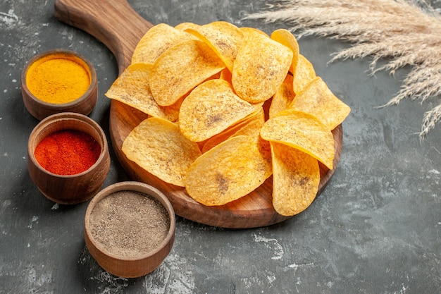 Close up view of delicious potato chips spices with ketchup on gray table