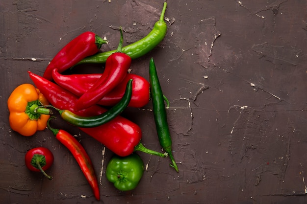 Free photo close-up view of different peppers on left side and brown background with copy space